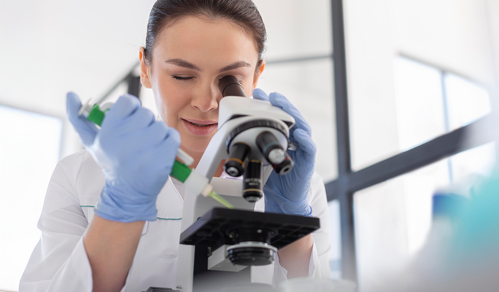 Mulher cientista utilizando um microscópio.